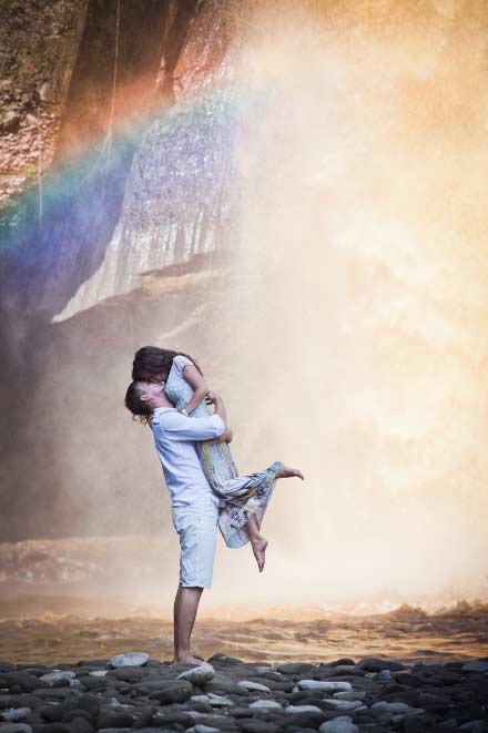 A guy holding a gal up while kissing her